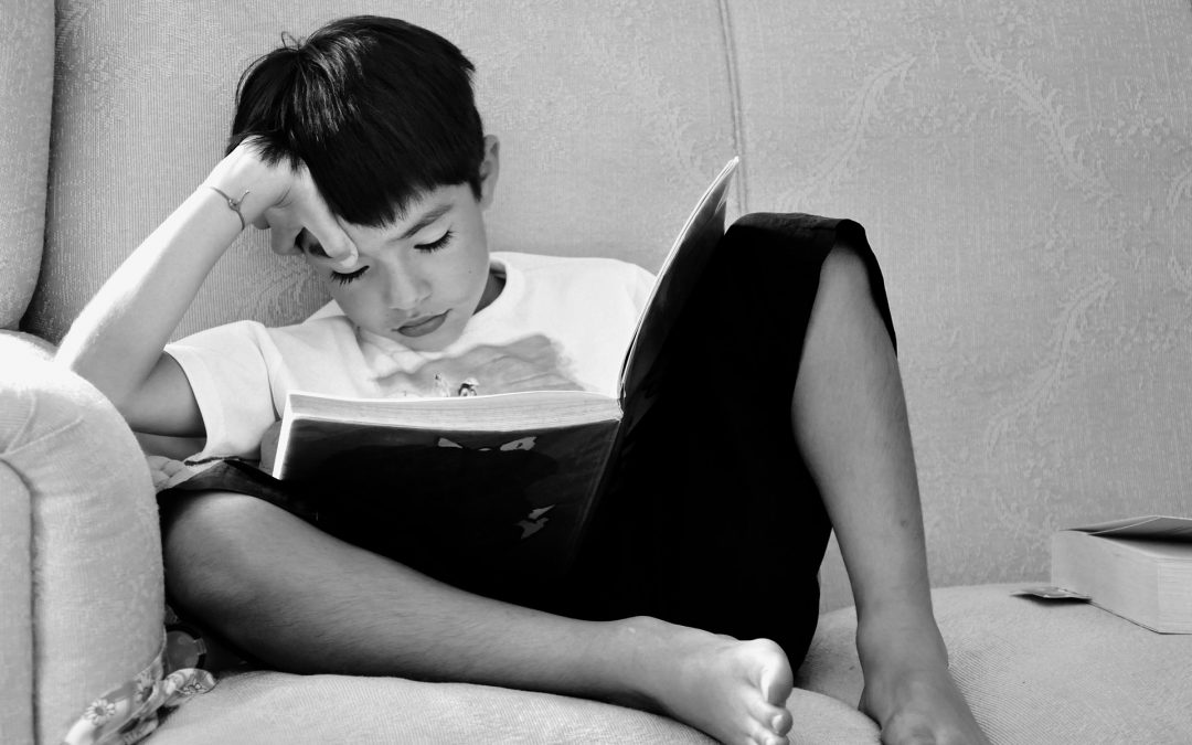 boy sitting on couch reading book
