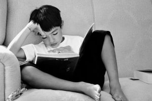 boy sitting on couch reading book